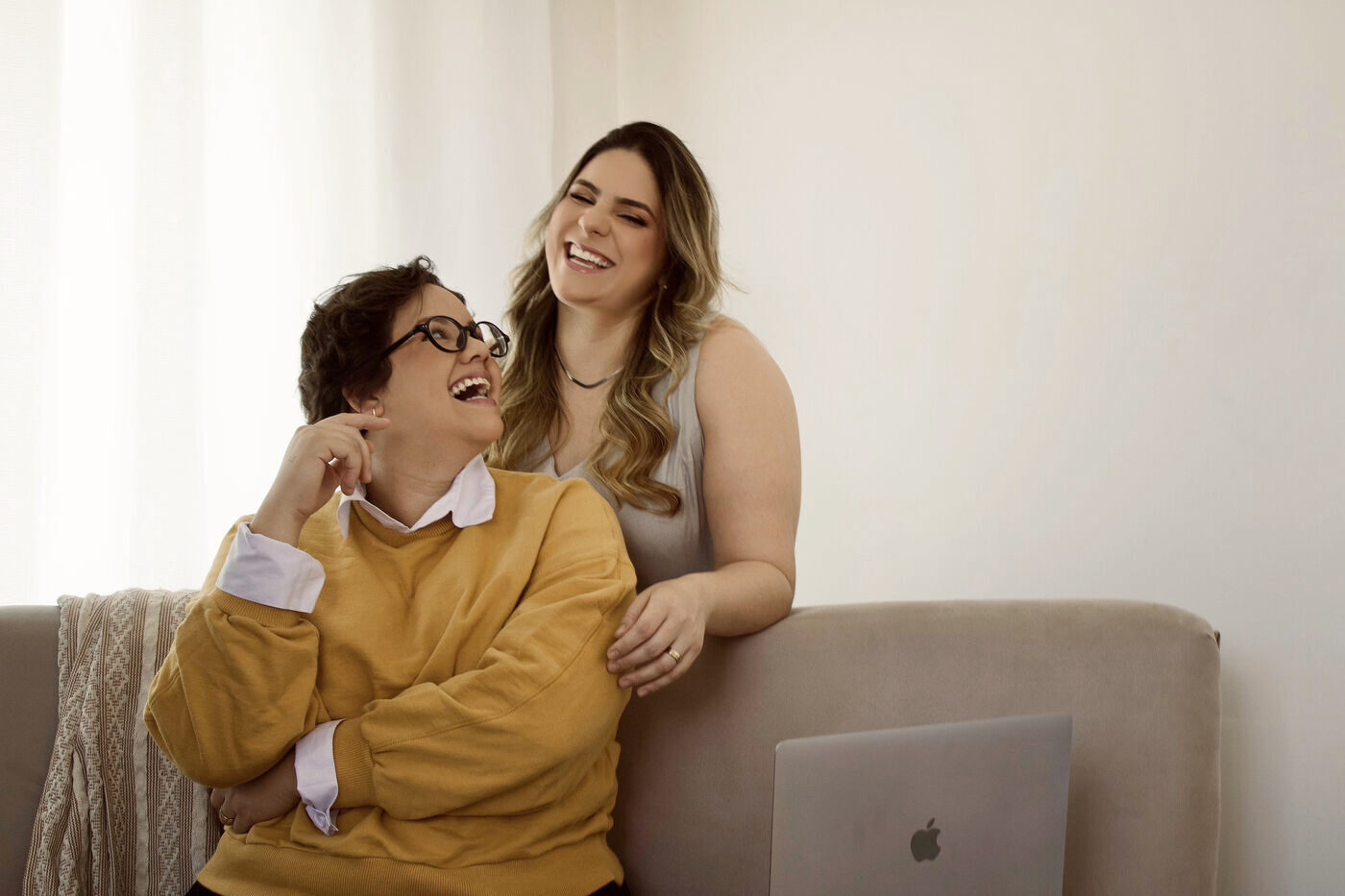 Magi e Ari, da Legato, rindo juntas num sofá